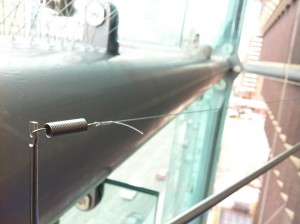 Bird wire deterrent system on a horizontal pipe of a glass canopy.
